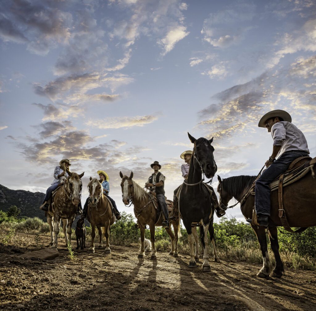 A group of people riding horses on top of a dirt field.